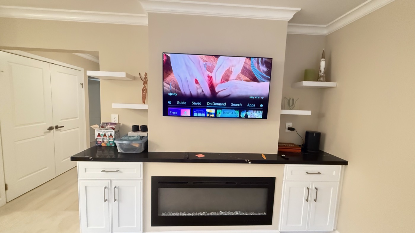 Television mounted above a white cabinet run with a linear electric fireplace