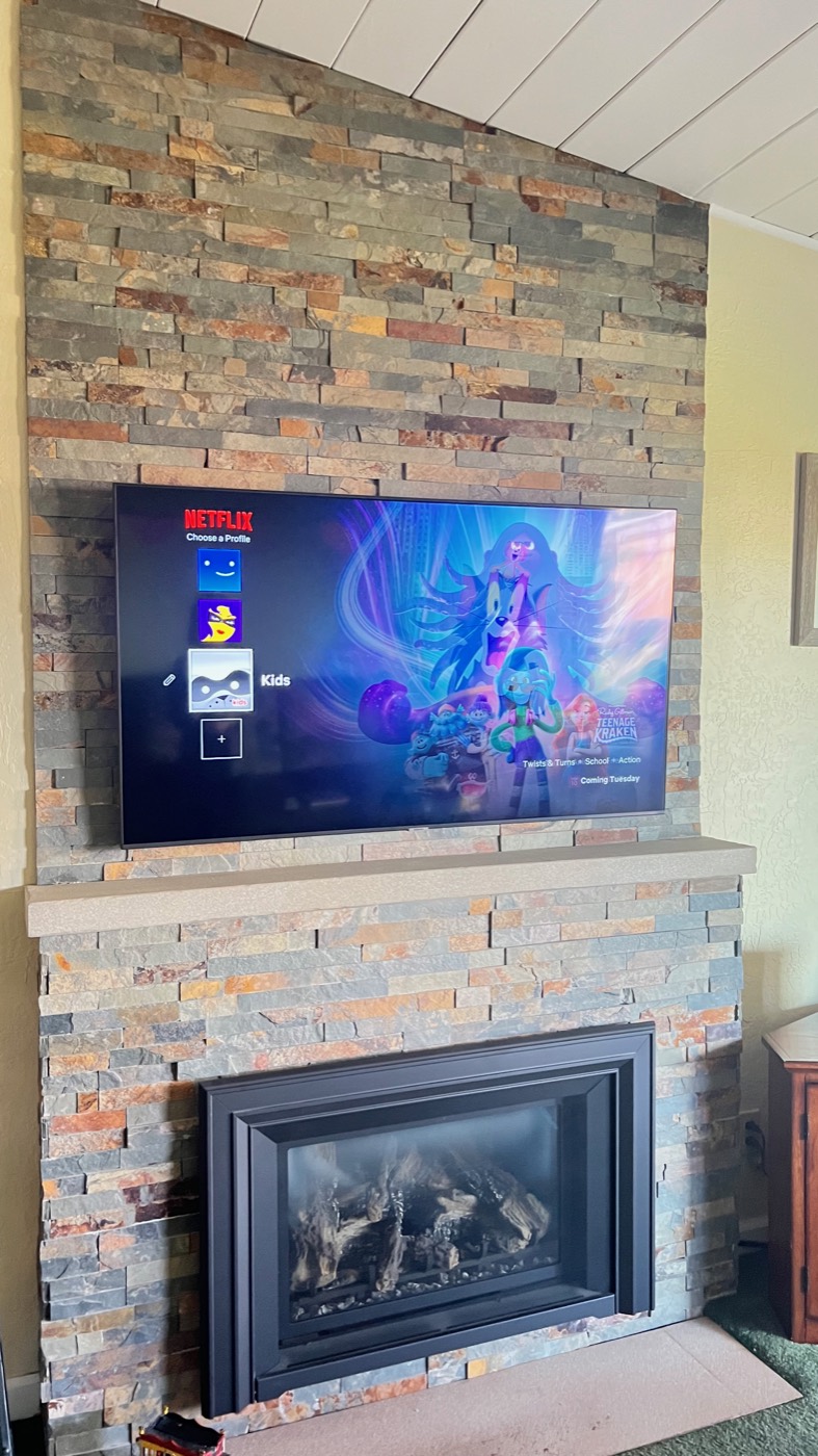 Television mounted on a stacked stone fireplace chimney
