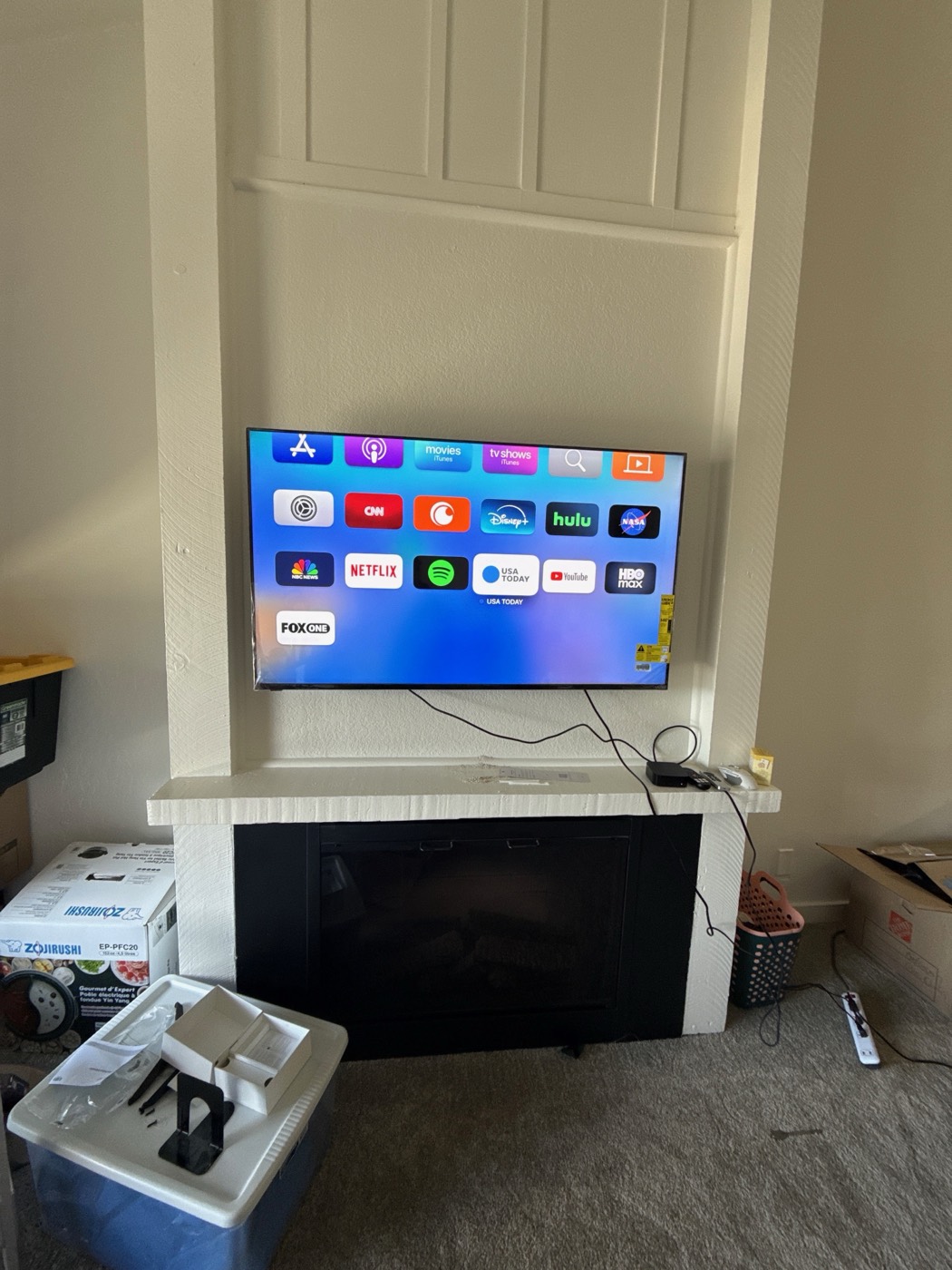 Large television mounted above a fireplace showing streaming apps