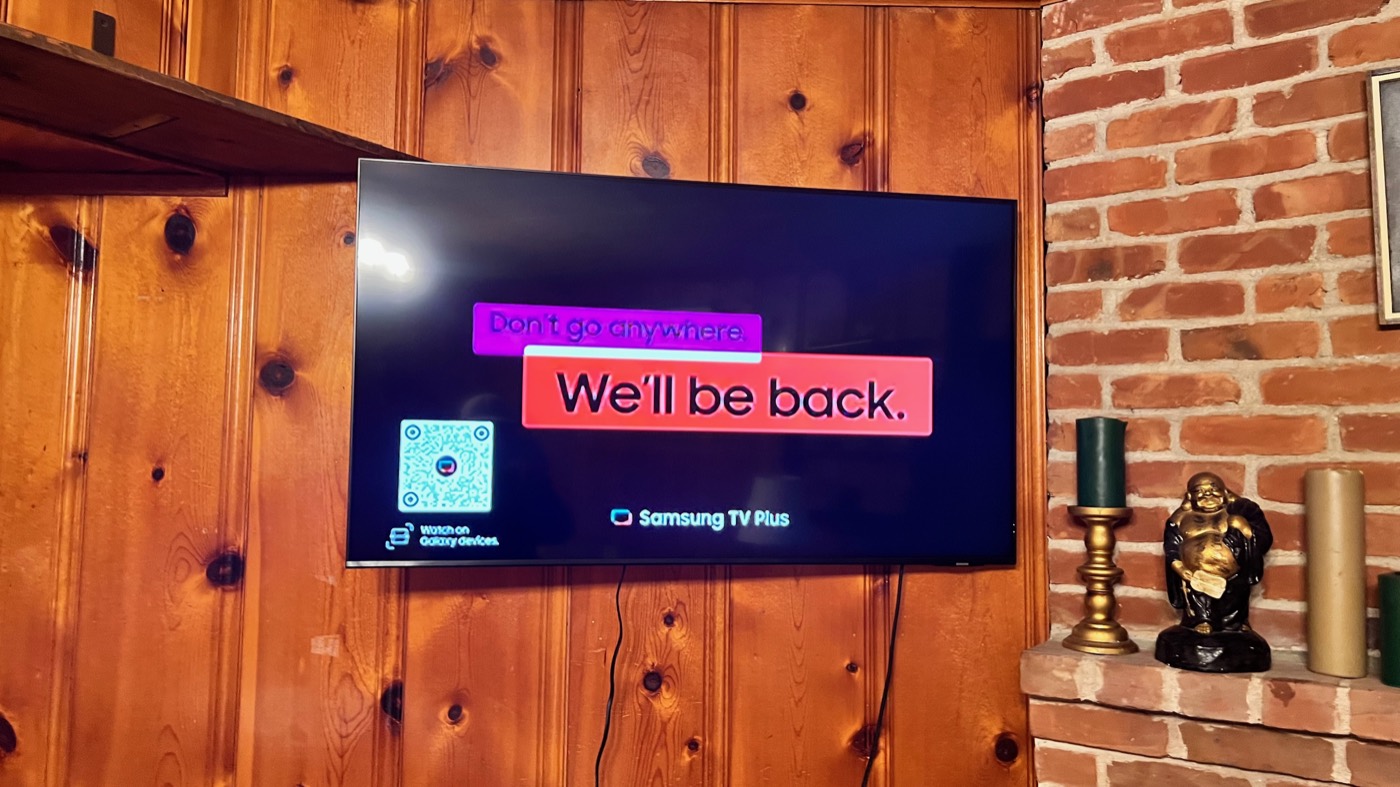 Television mounted on a knotty pine panelled wall beside brick